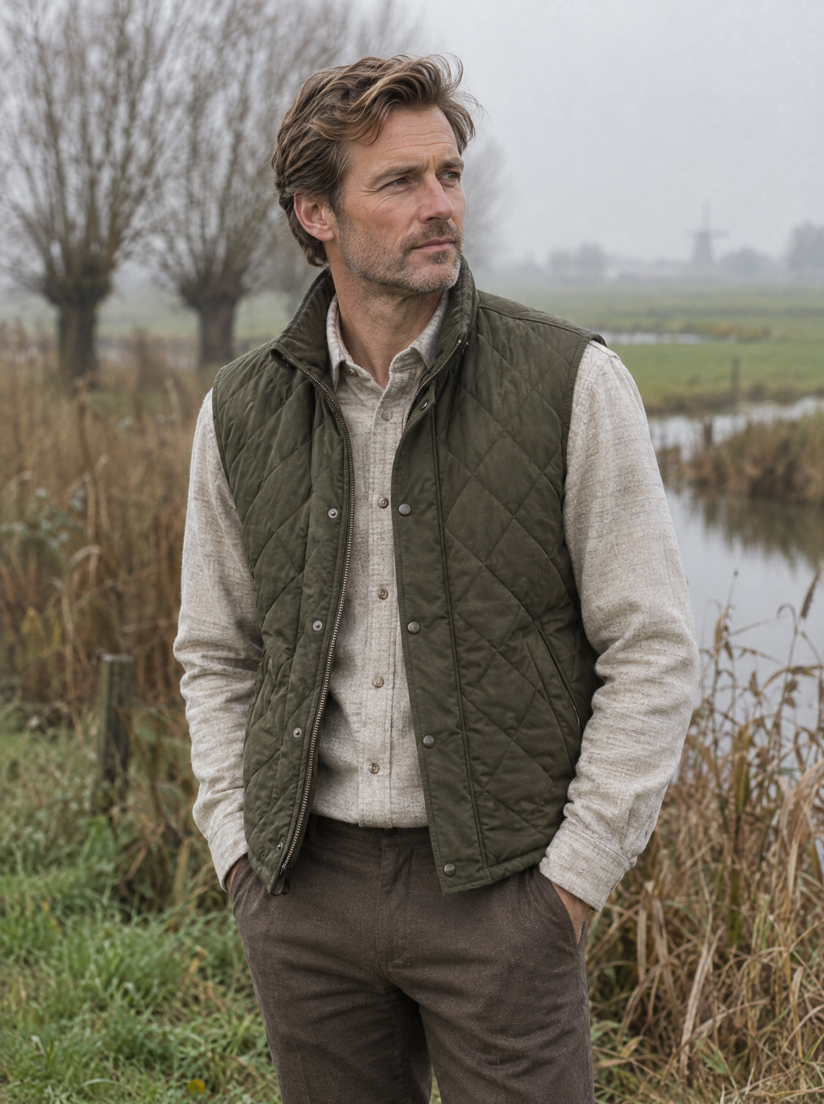 Man in olijfgroen gewatteerd bodywarmer in een mistig polderlandschap
